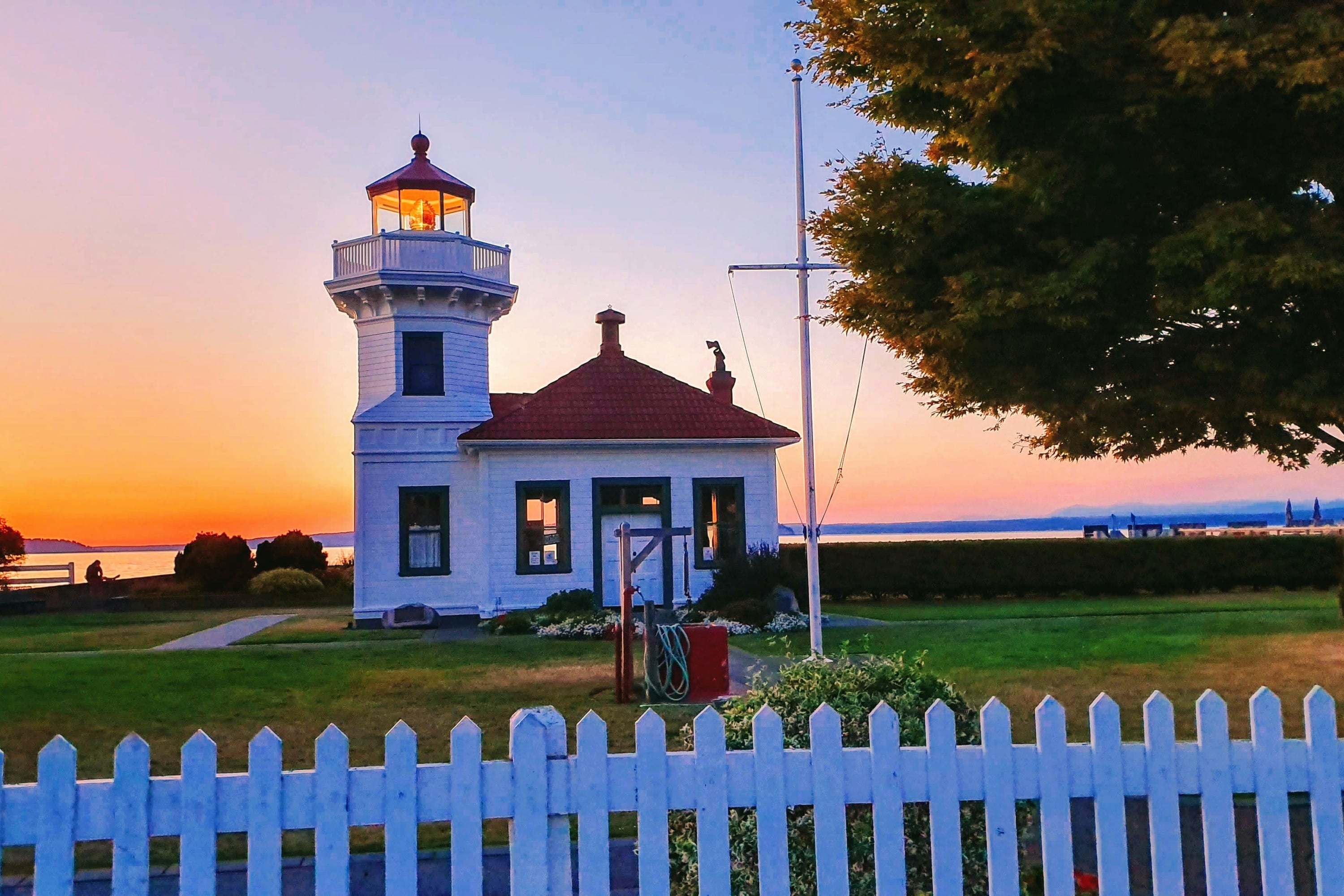 The Mukilteo lighthouse behind a white picket fence at sunset